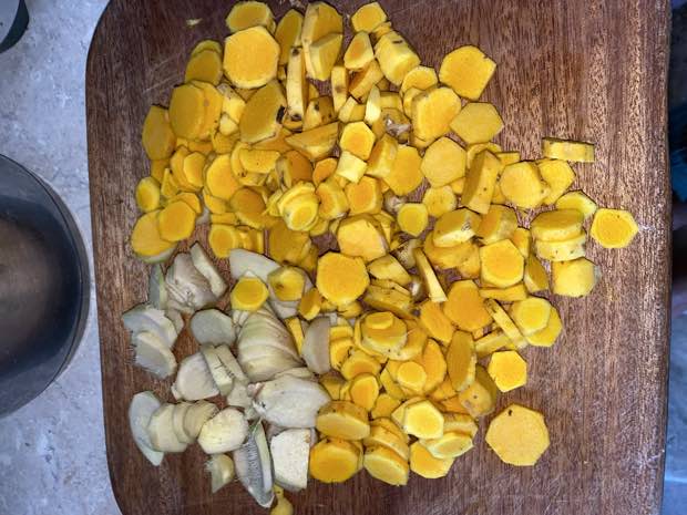 Turmeric sliced into thin rounds on a wooden board