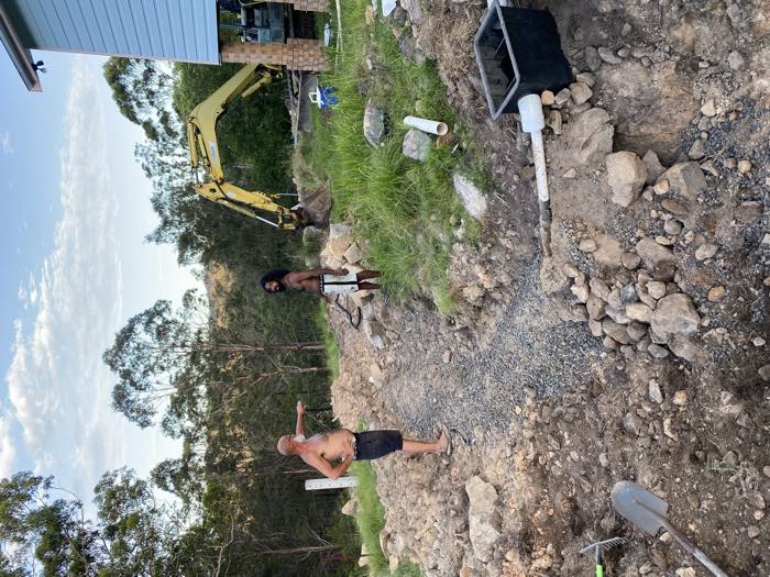 The trench backfilled with gravel, an outlet pit and pipe at the lower end
