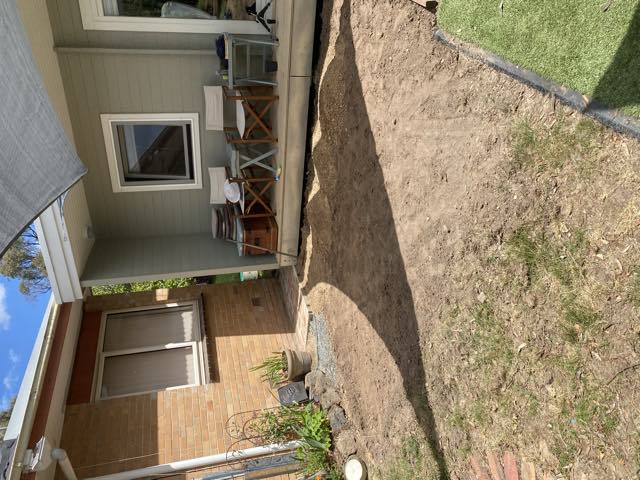 A patch of bare dirt between the house and a studio building