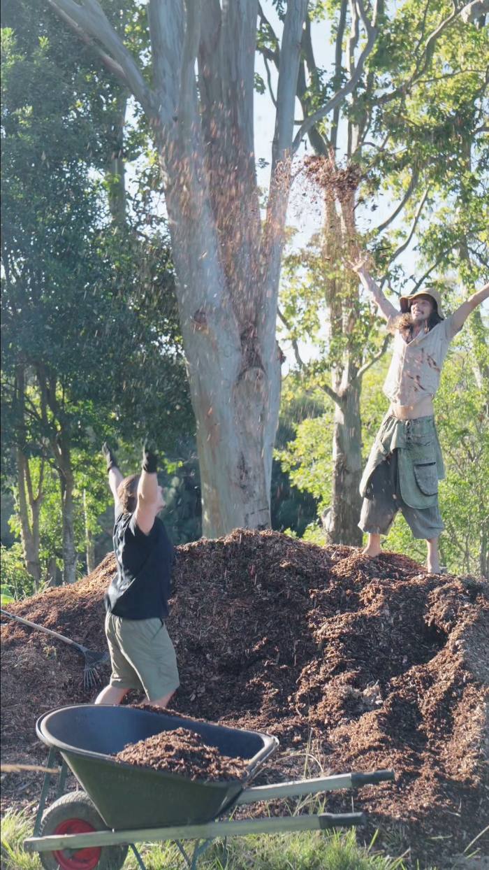 Two pairs of hands moving mulch
